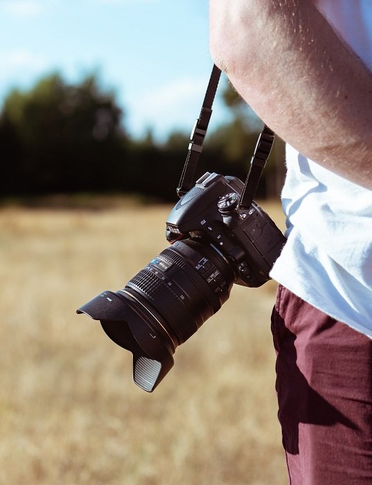 Someone carrying a Nikon DSLR with a shoulder strap