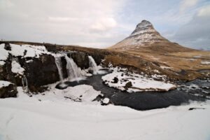 Snowy landscape with a waterfall and green mountain in the distance