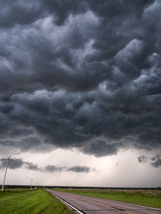 Dark clouds over a flat landscape with a road