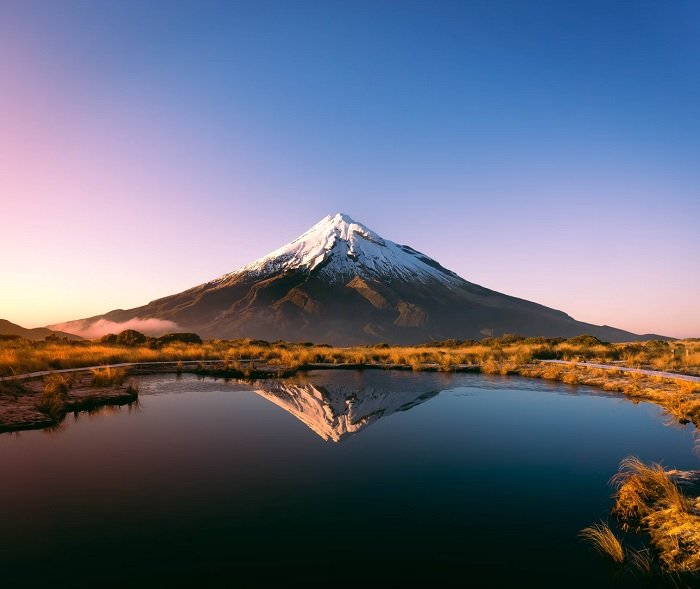 Landscape image of a solitary mountain reflected in the water of a lake in the foreground