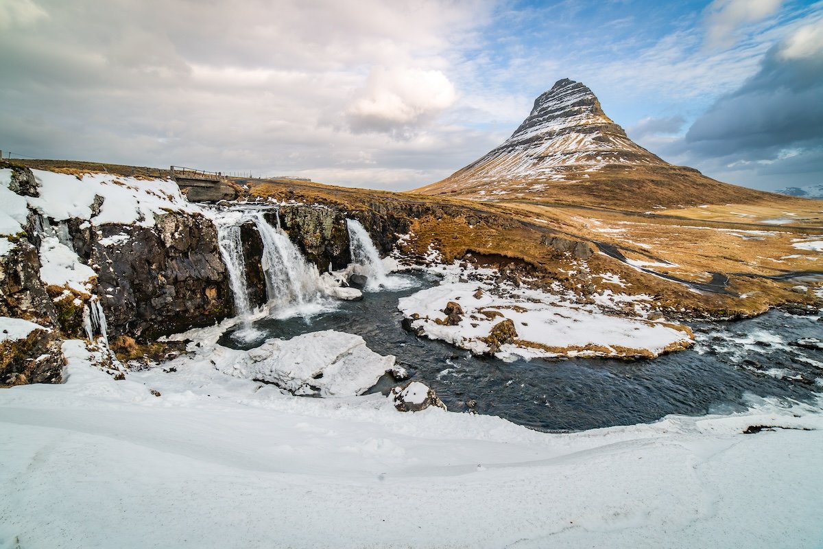 photo of a waterfall and mountain in a partly snowy scene