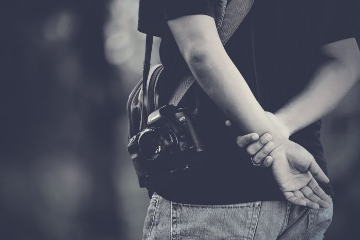 A black and white close up of a man with an inconspicuous camera with 50mm lens for taking candid street photos