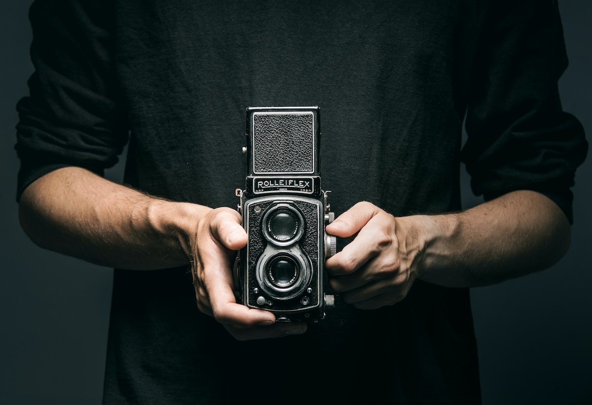 A person holdng a twin-relfex lens Rollieflex camera