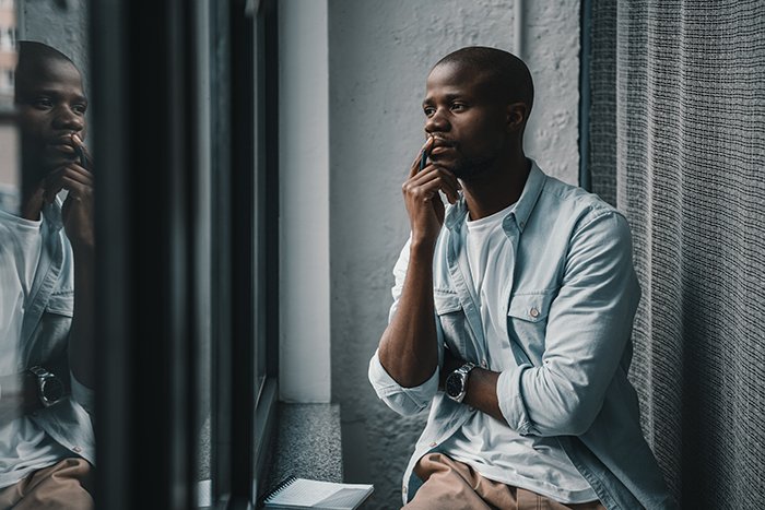 Portrait of young thoughtful man looking out the window.