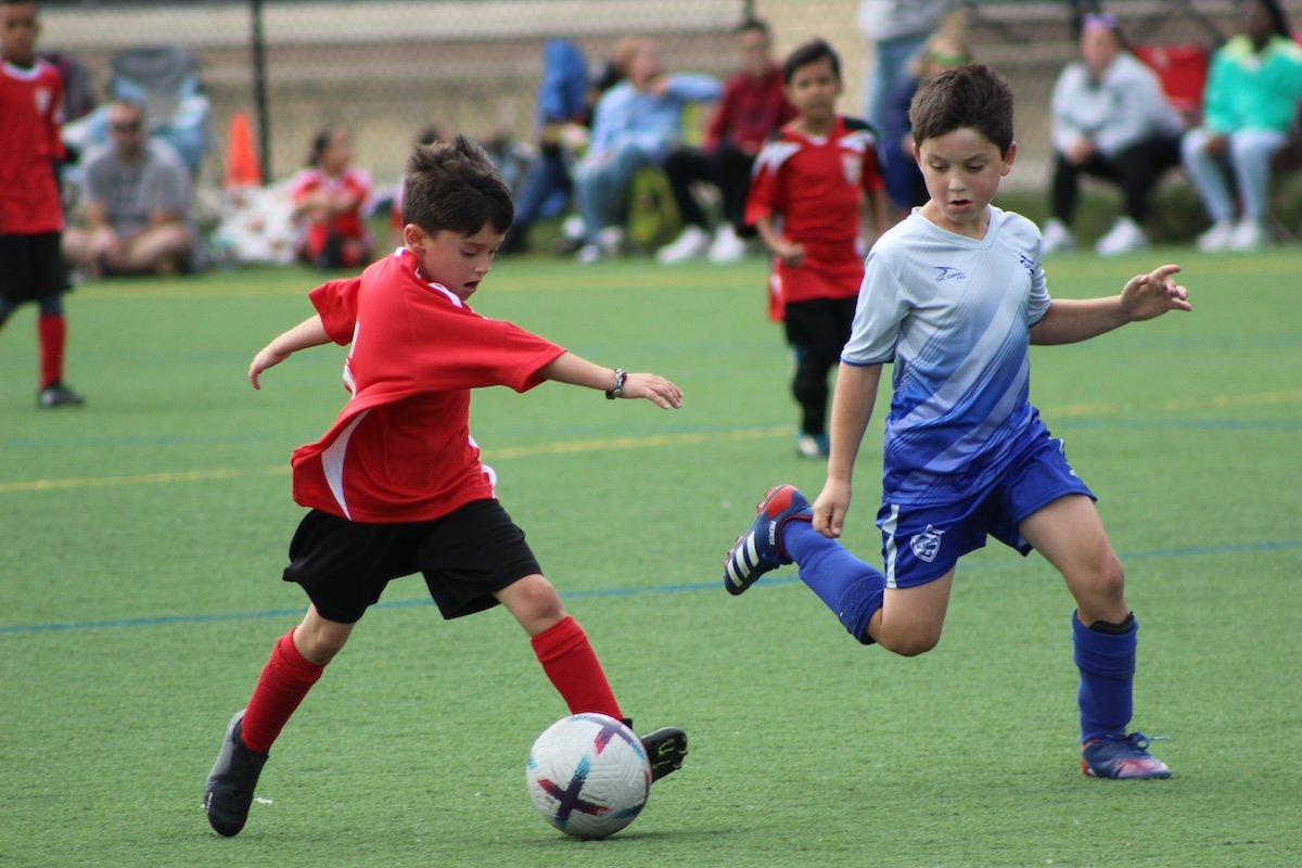 Two kids playing soccer on a playing field