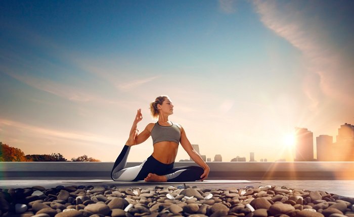 Woman on a rooftop doing yoga at sunset