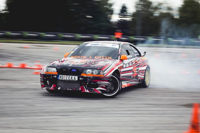 Racing car taking a bend at high speed with smoke coming from rear wheels