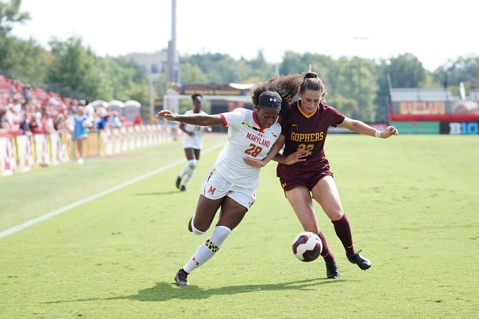 Two female football players going shoulder to shoulder for the ball