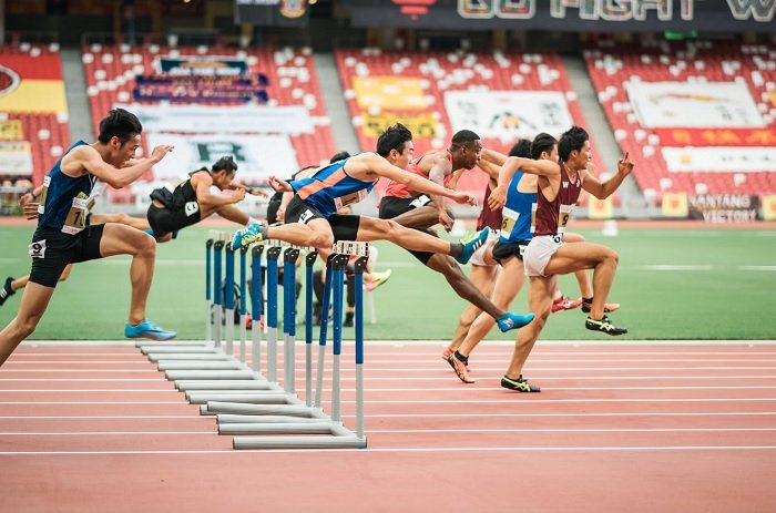 Hurdlers hurdling hurdles on an athletics track