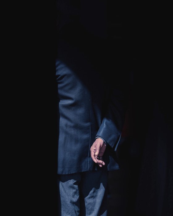 A creative image of a man in a business suits, most of his body covered in shadow