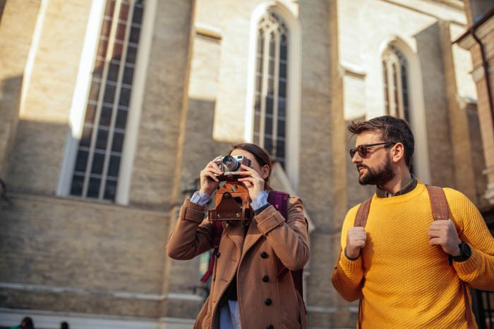 A travel photographer taking an architectural photograph beside her boyfriend