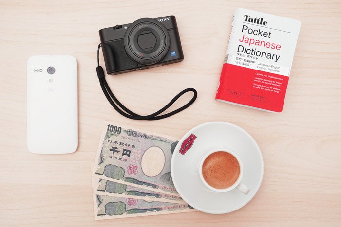 Accessories for travel photography like a guidebook, camera, local money and phone