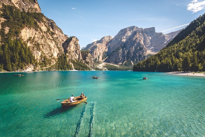 two people in a rowboat on a lake in front of a beautiful mountain range